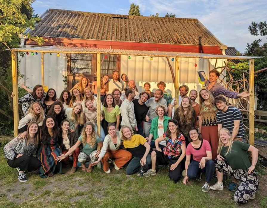 Groepsfoto van Koor Saman, op een grasveld voor een schuur